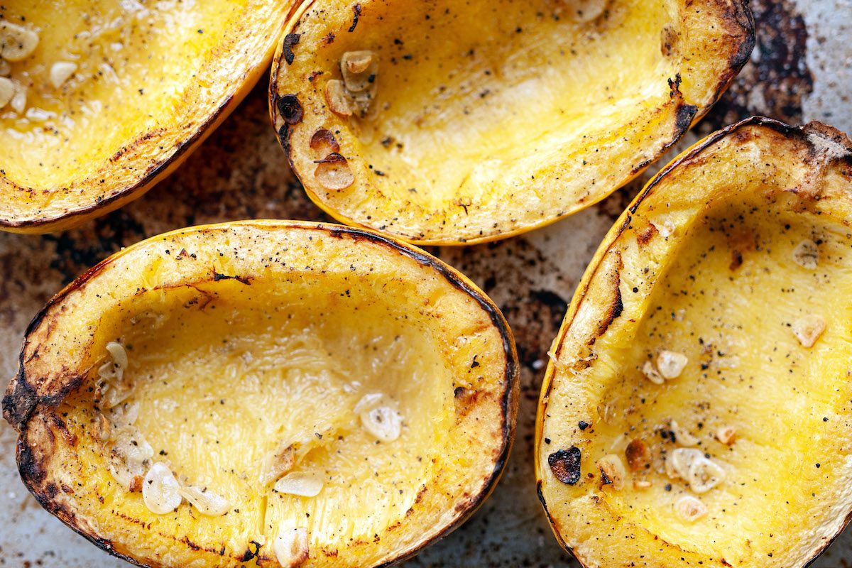 A close up of baked spaghetti squash on a baking sheet just out of the oven.