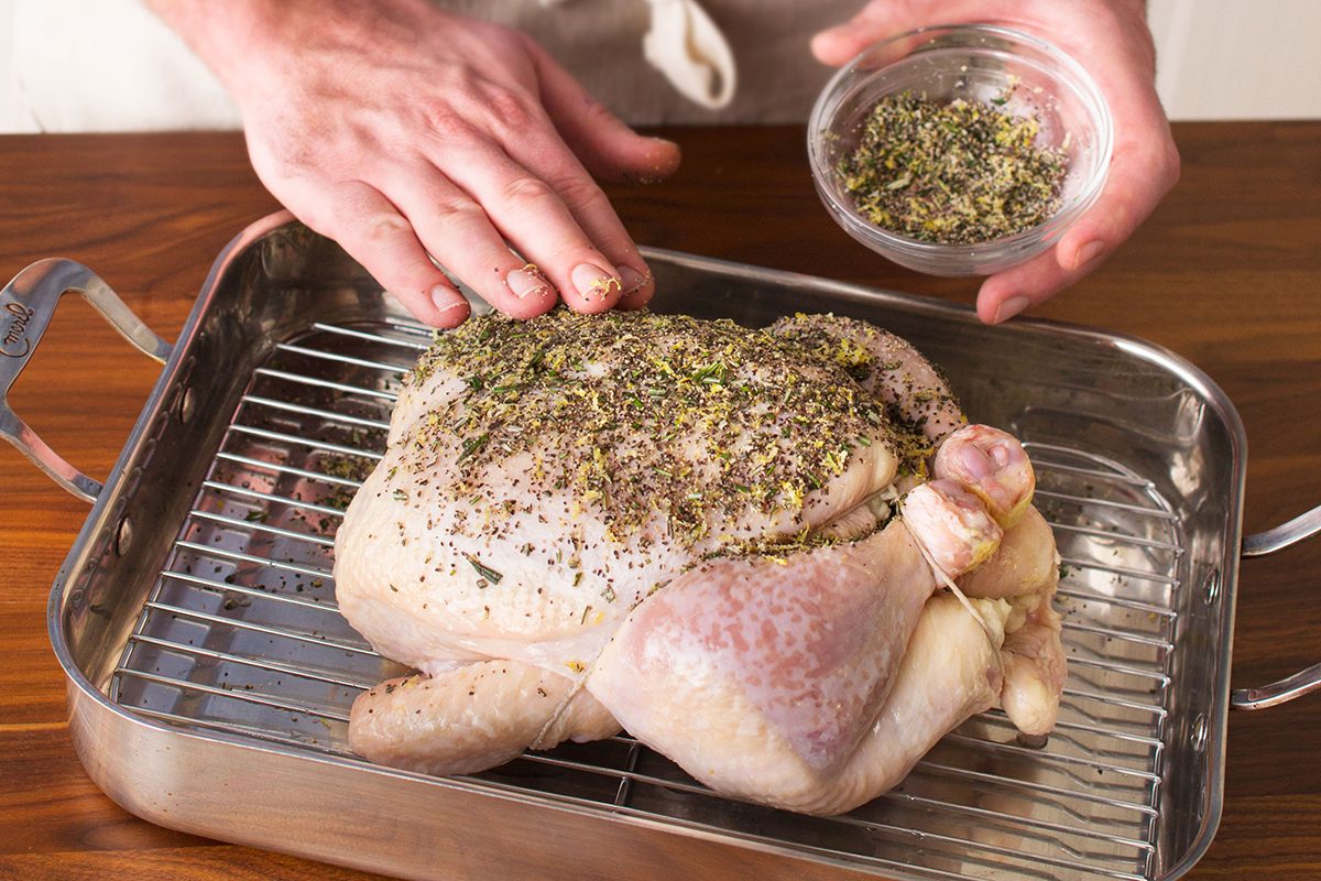 Seasoning a raw chicken by hand