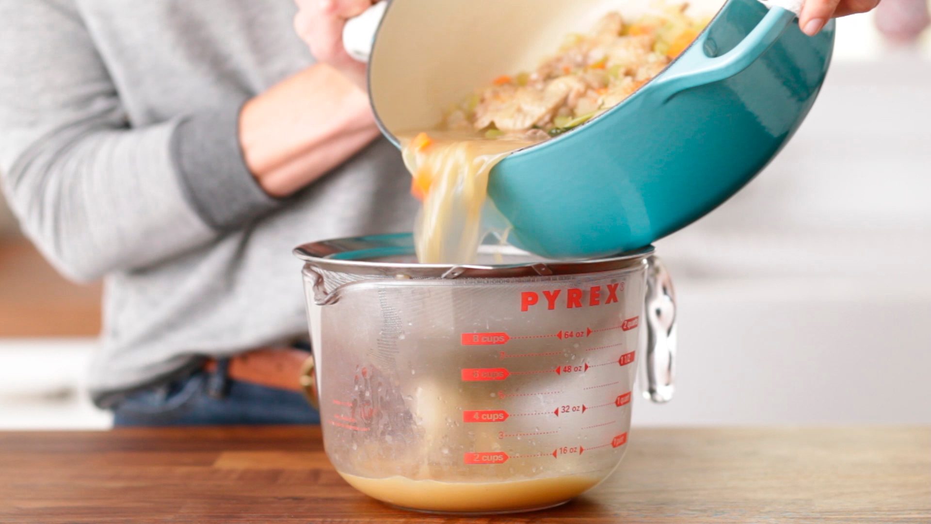 Person straining the liquid away from their turkey bones and vegetables