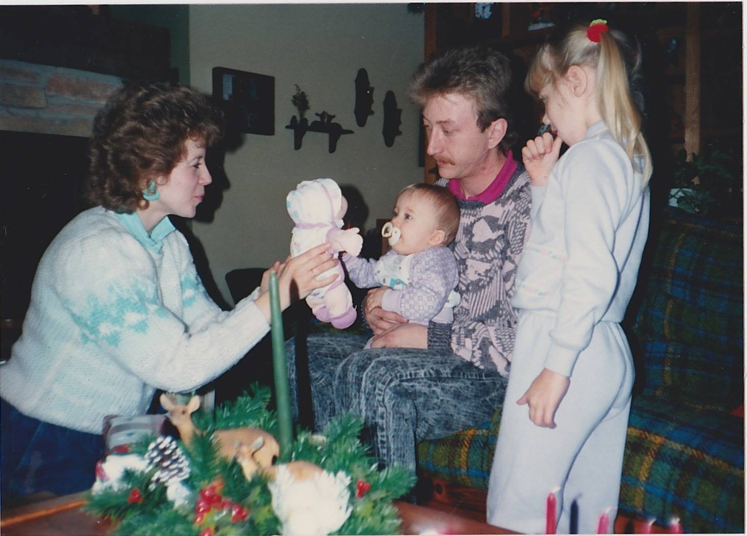 Mother, father and older sister presenting the family baby with a toy baby
