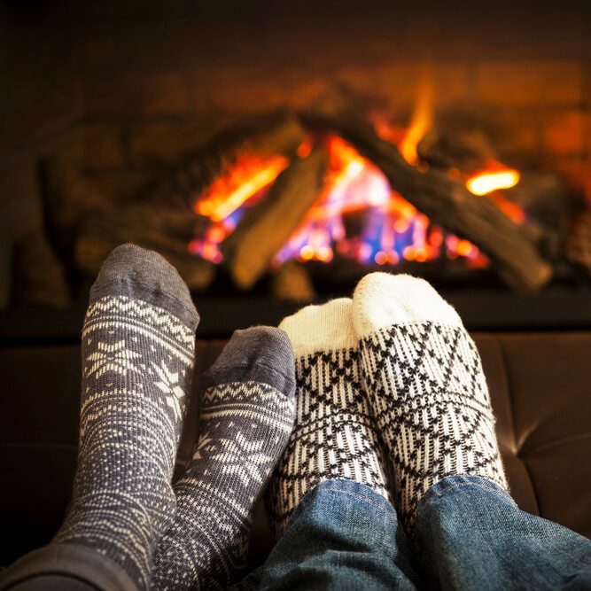 Feet in wool socks warming by cozy fire