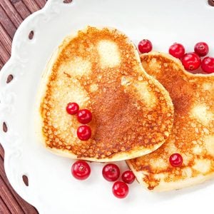 Homemade Heart shaped pancakes with cranberries on white porcelain plate