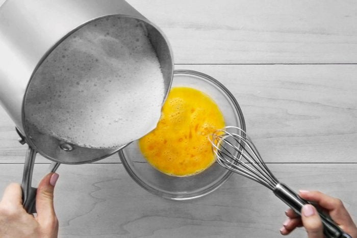 Pouring flour and milk mixture into beaten eggs