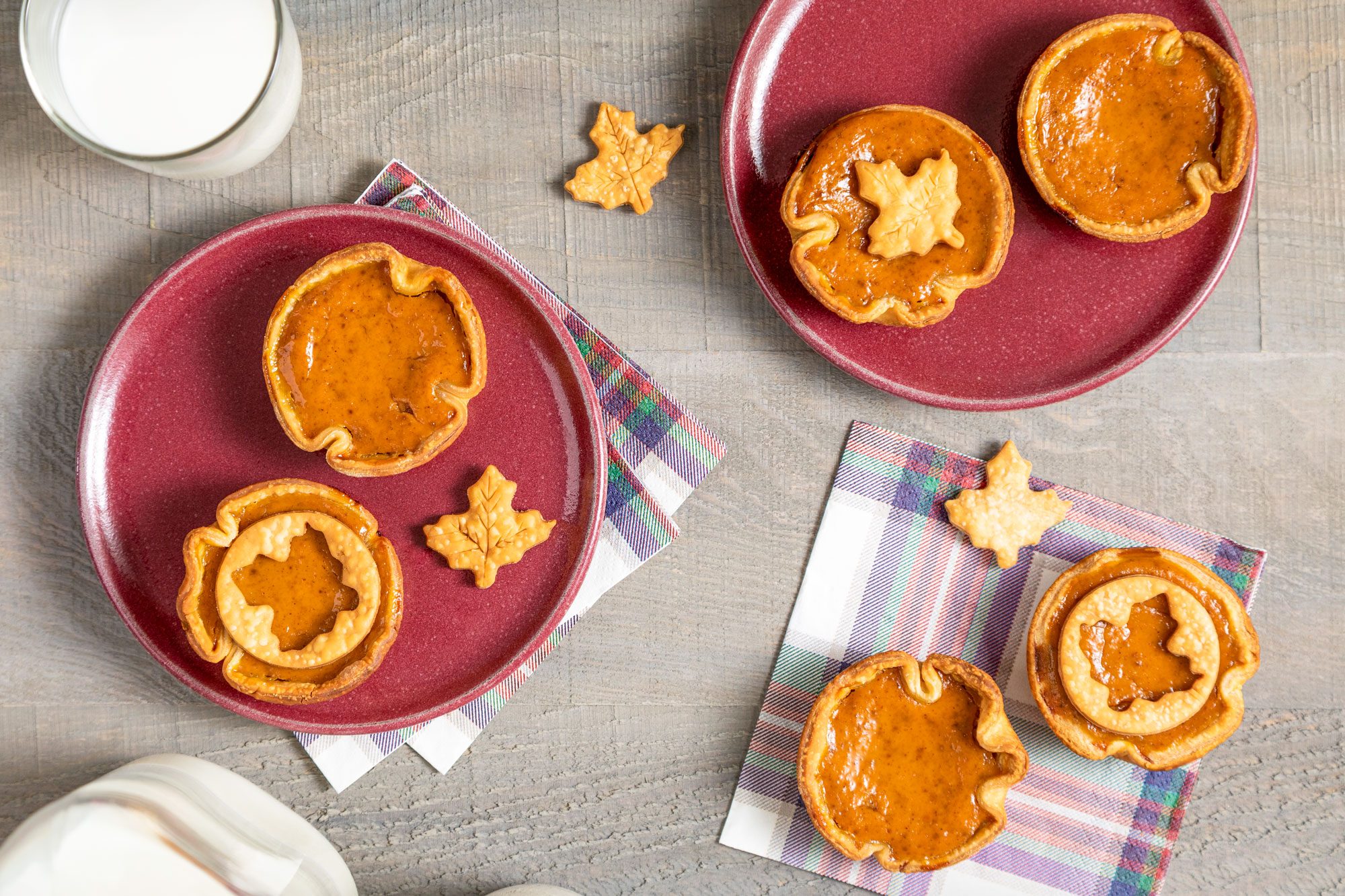 Mini Pumpkin Pies Served in Small Maroon Plates on Wooden Surface