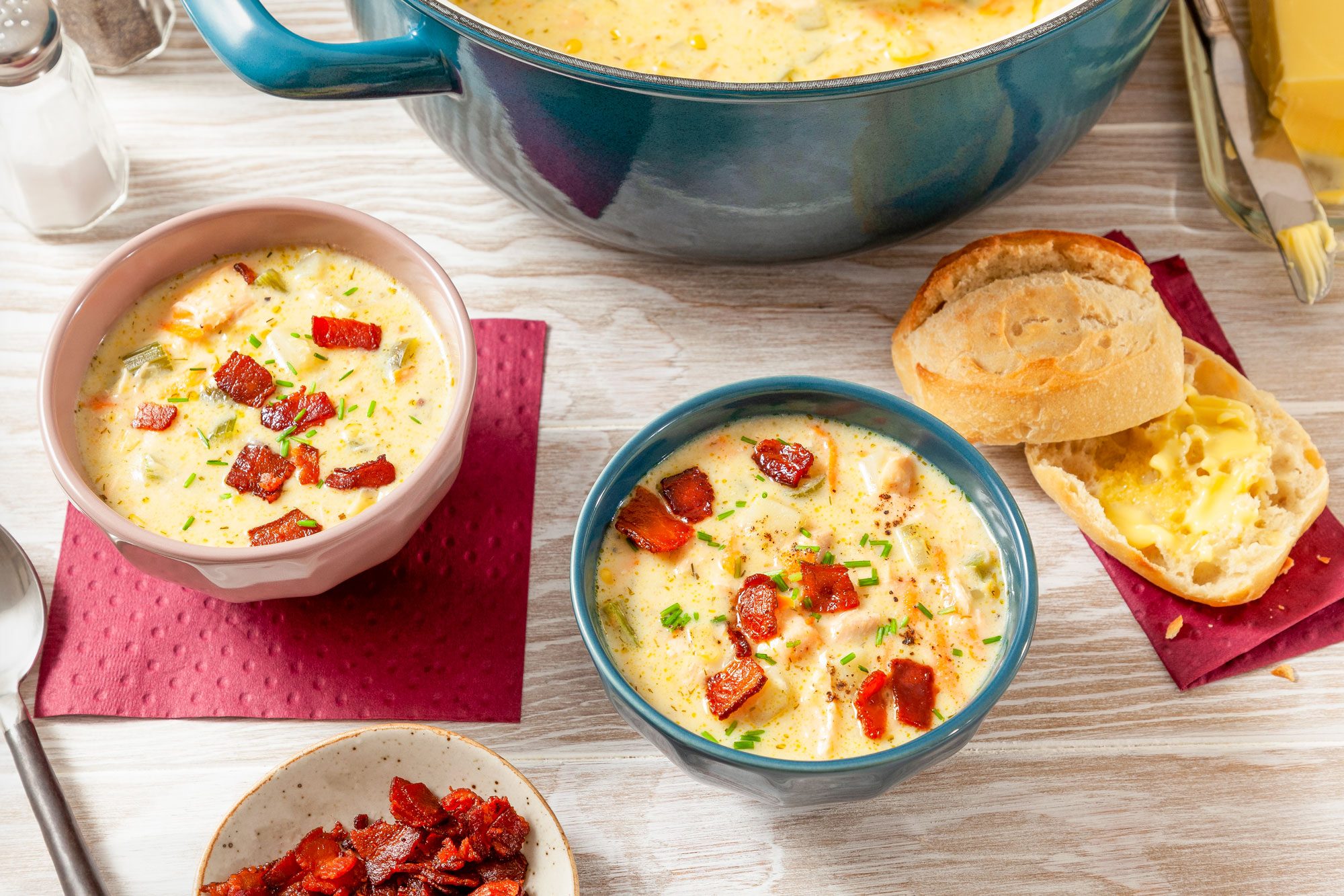 Salmon Chowder Served in Two Bowls with Breads on Wooden Surface