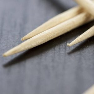 Pile of wooden toothpicks scattered randomly on a grey background for cleaning between the teeth after a meal in a personal hygiene concept