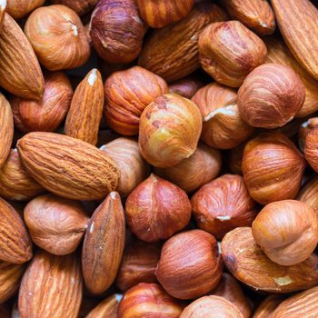 Nuts pile background. Cashew, almond, hazelnut mix closeup. Organic food rustic banner template. Tasty healthy snack.