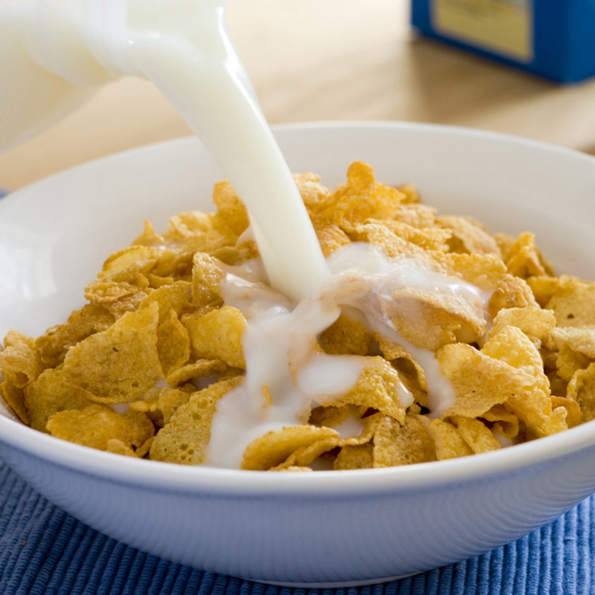 milk being poured into a bowl of cereal