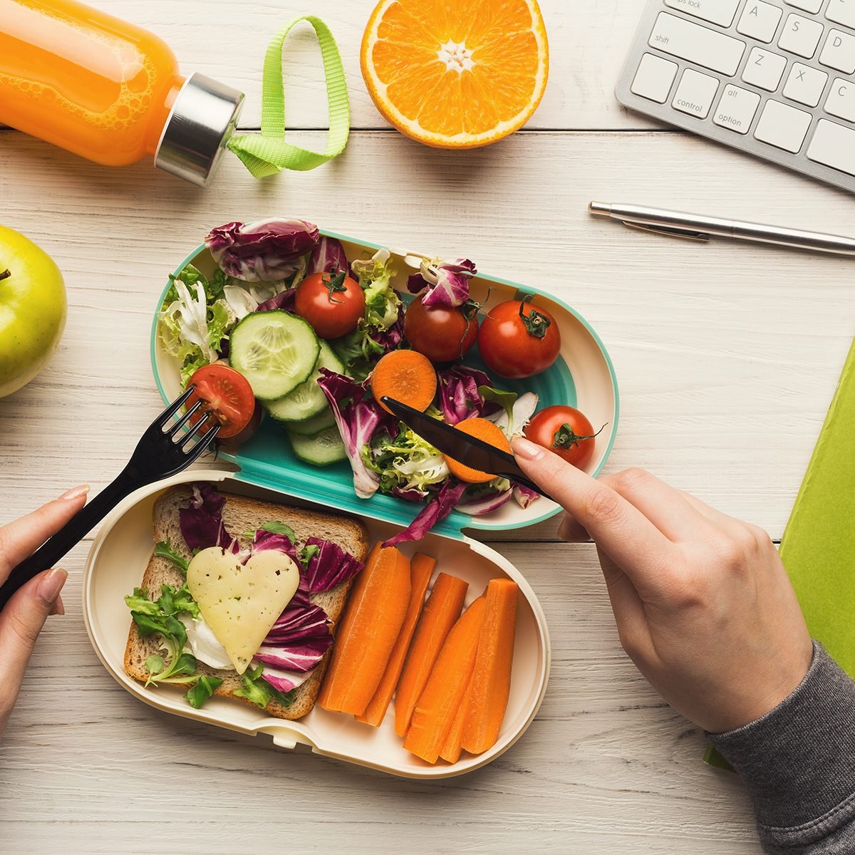 Healthy snack at office workplace. Businesswoman eating organic vegan meals from take away lunch box at wooden working table with computer keyboard; Shutterstock ID 1016932243; Job (TFH, TOH, RD, BNB, CWM, CM): TOH