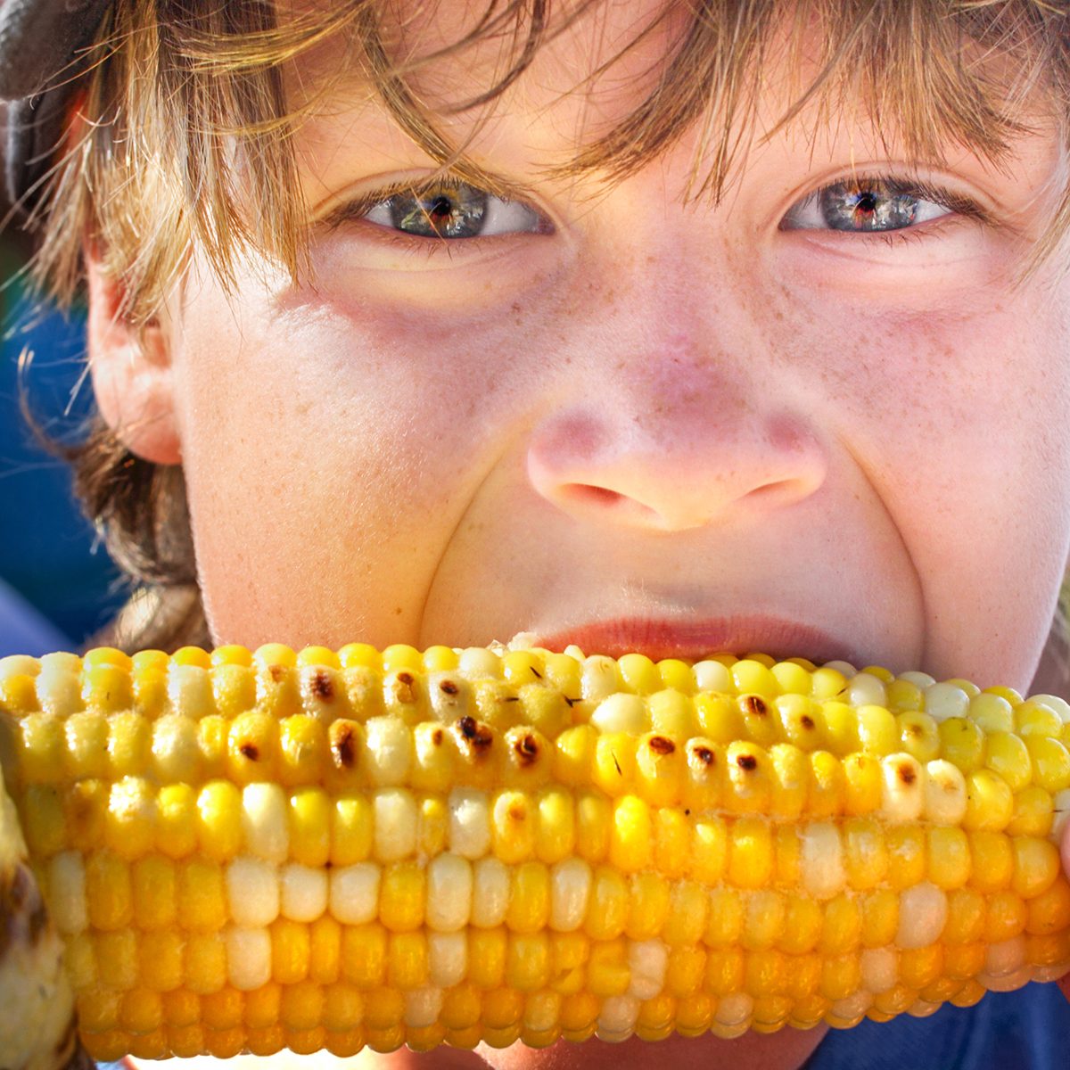 Happy boy eating corn on the cob