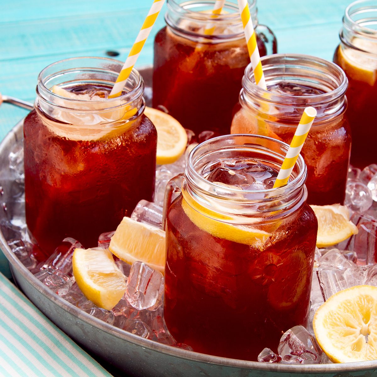 Mason jar mugs filled with iced tea and fresh lemon 