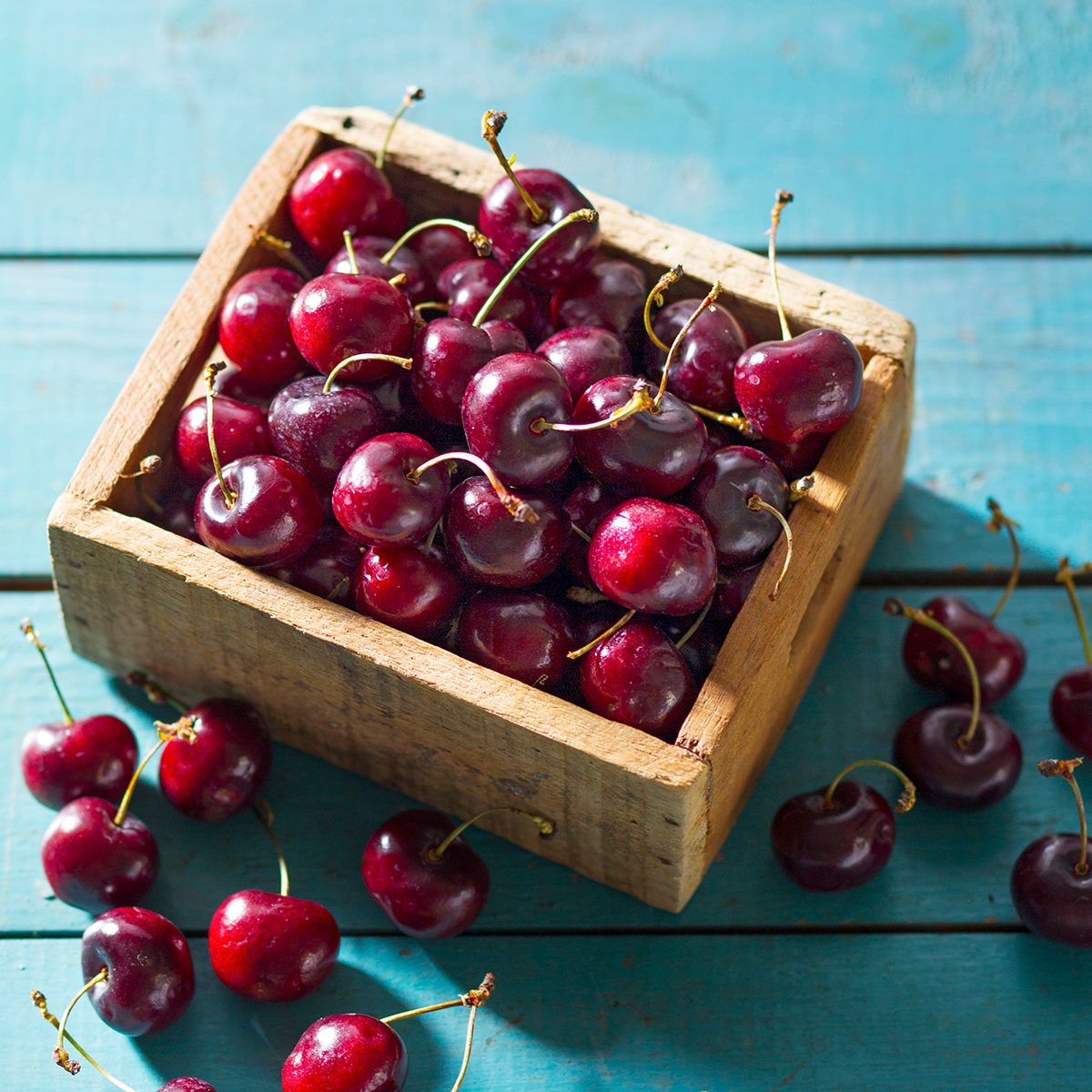 Fresh Bing Cherries In Wooden Box On Blue Wood Surface