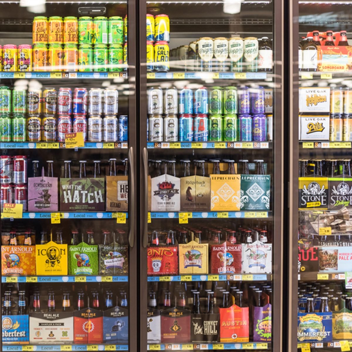arious bottles of craft, microbrew, IPA, domestic and imported beers from around the world on shelf display in supermarket cooler.