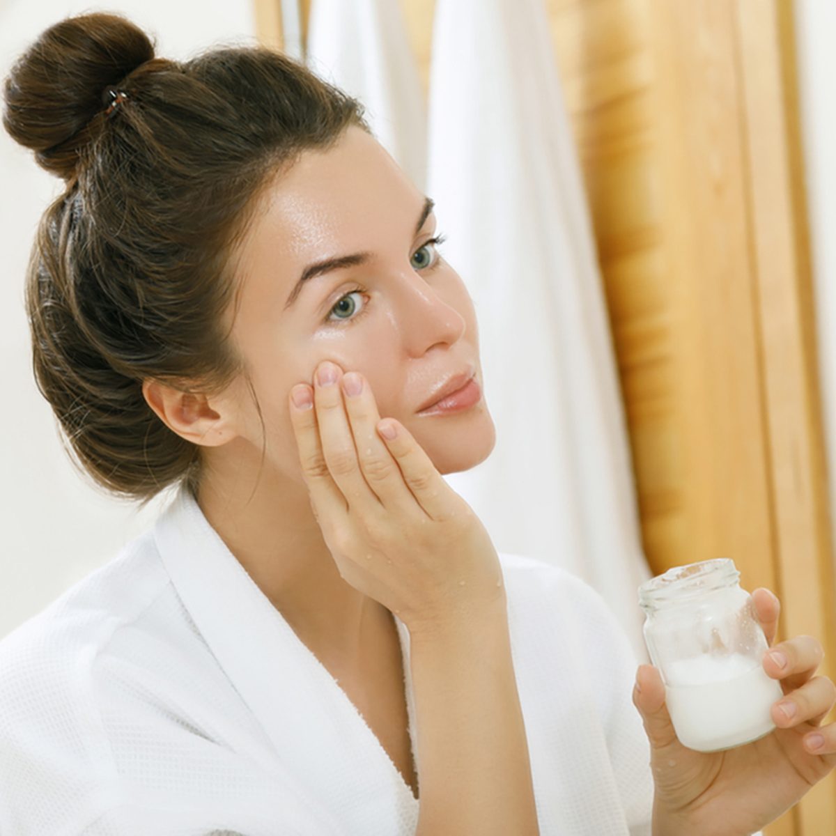 Woman is moisturizing her skin with a coconut oil