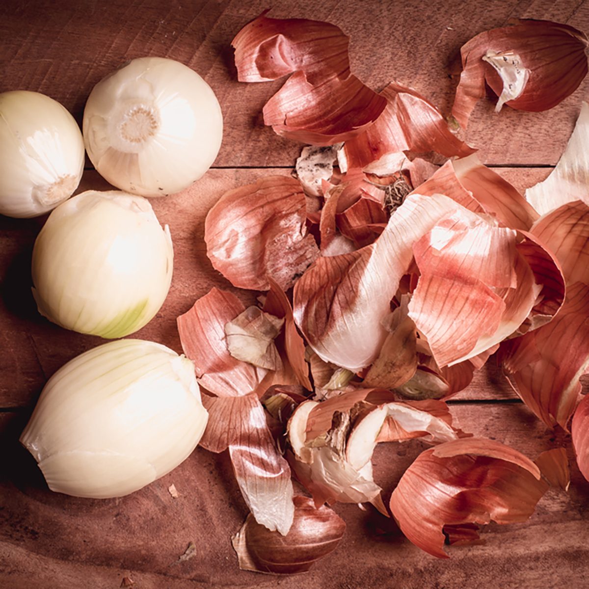 Onion peeled and skin on wooden background