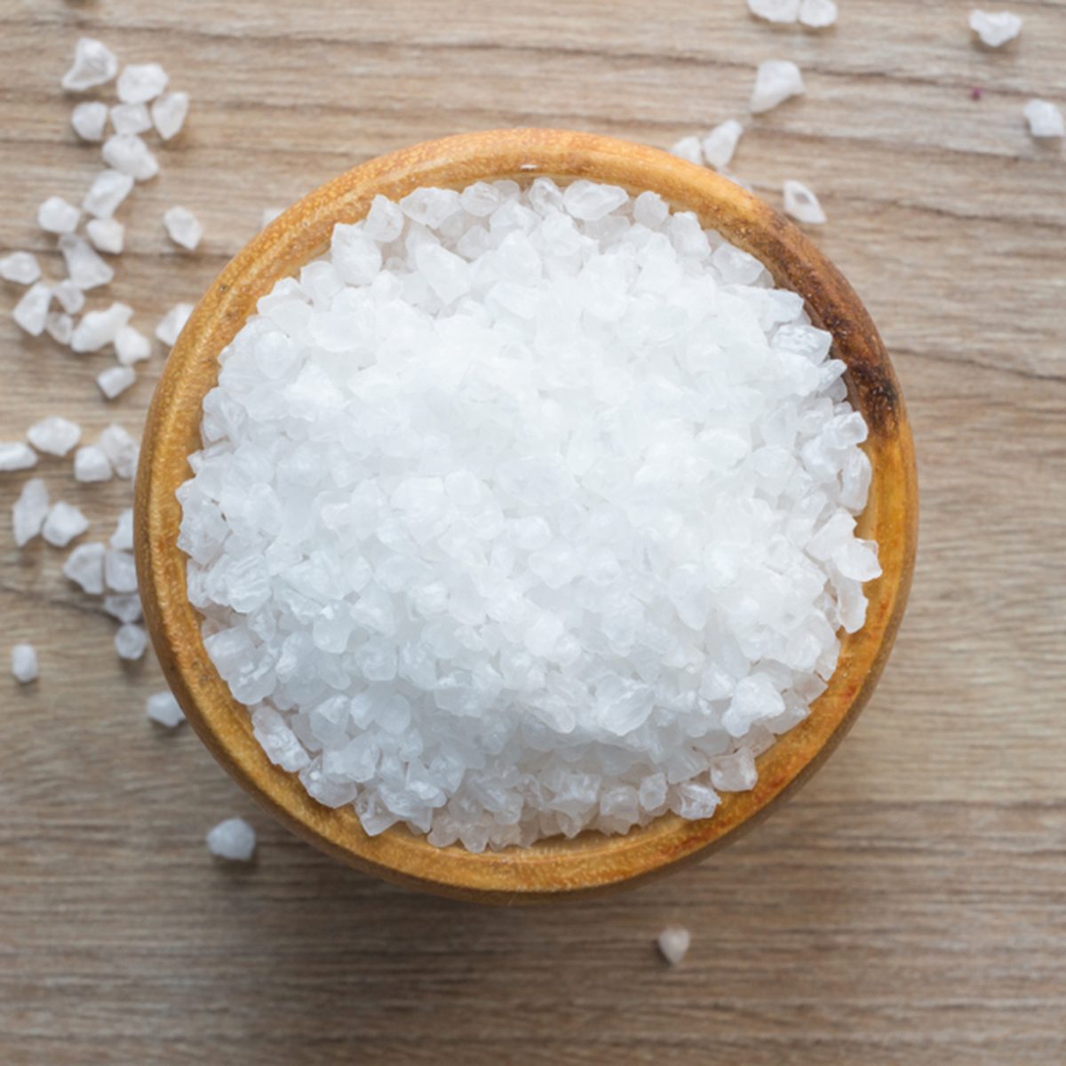 Top view of Salt or sea salt in a wooden bowl on a wooden table background.