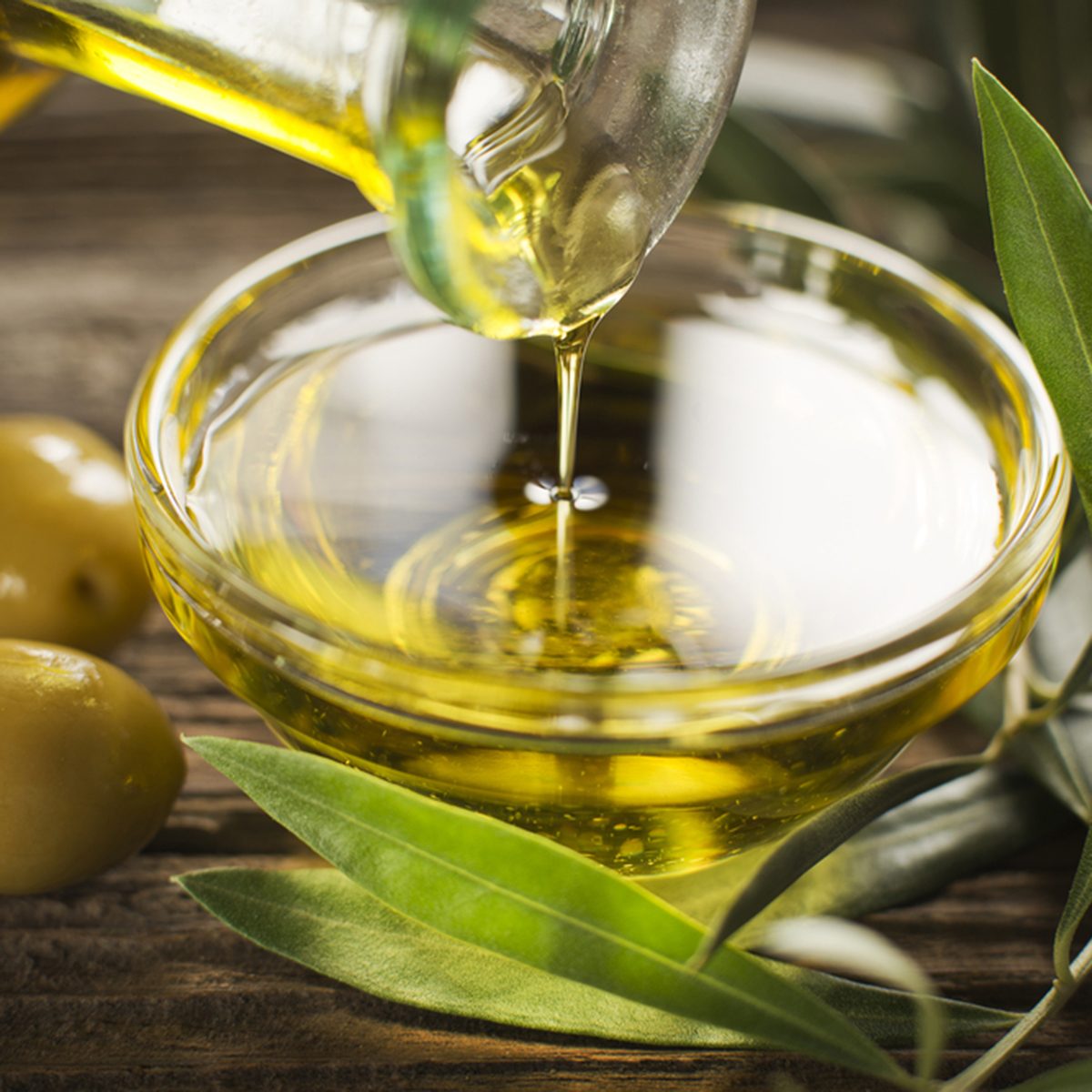 Bottle pouring virgin olive oil in a bowl close up