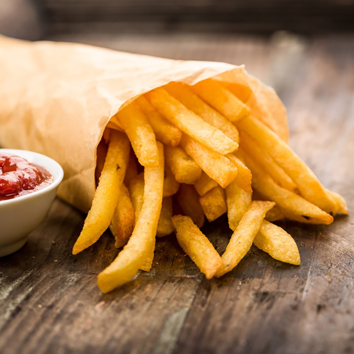 Fresh fried french fries with ketchup on wooden background