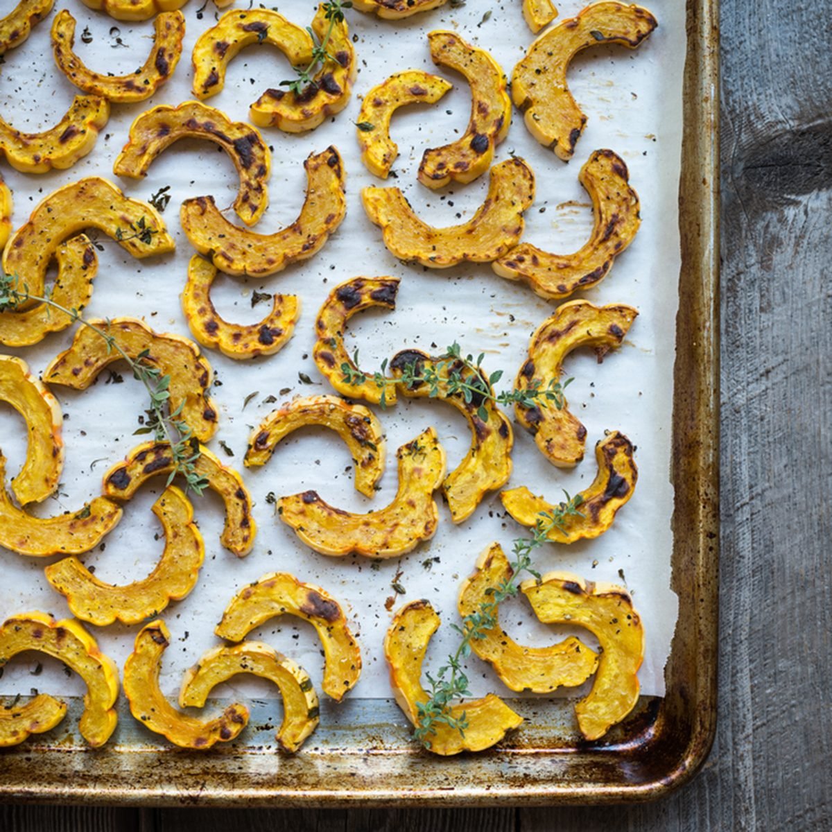 Sheet pan with freshly roasted delicata squash on parchment