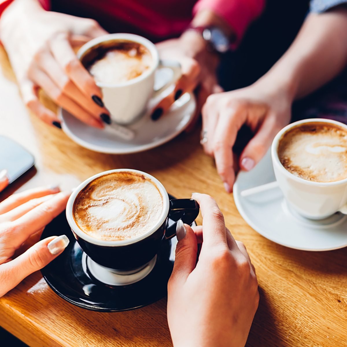 Closeup of hands with coffee cups in a cafe
