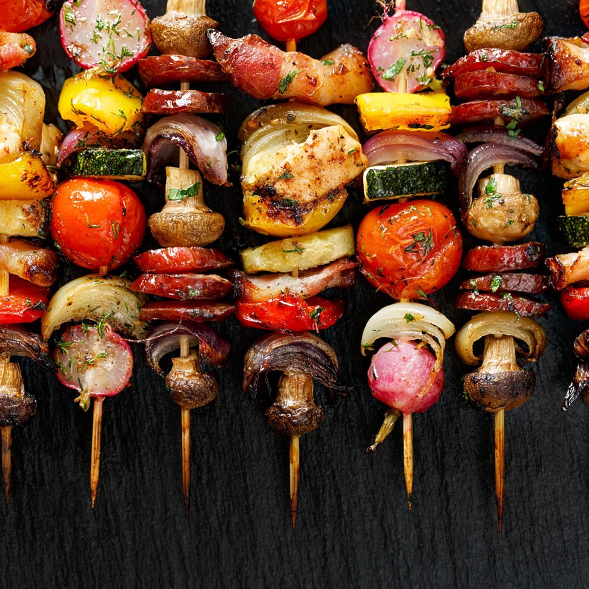 Grilled vegetable and meat skewers on the black stone background