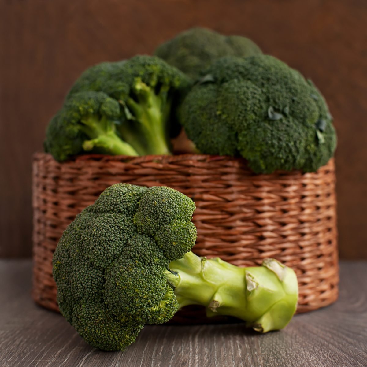 Broccoli cabbage in a wicker basket. A lot of broccoli in a wicker box on a brown background.