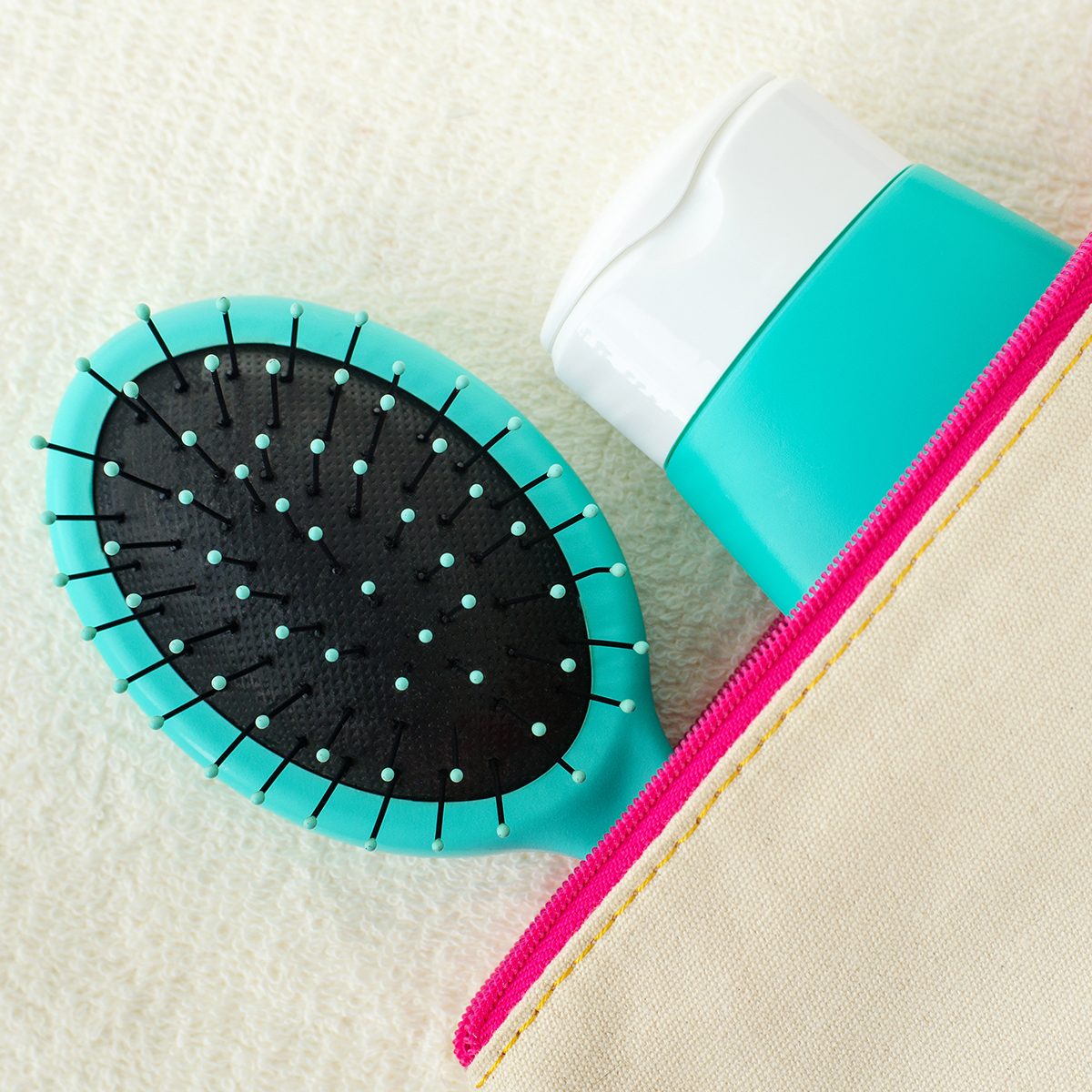 Hair shampoo (mask, conditioner, face cream, sunscreen lotion) and hair brush in the small make-up pouch. Top view, copy space.
