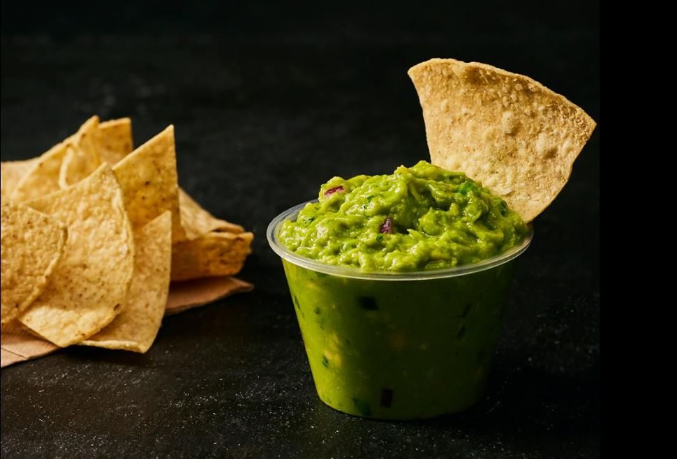 Small cup of guacamole beside chips at Chipotle