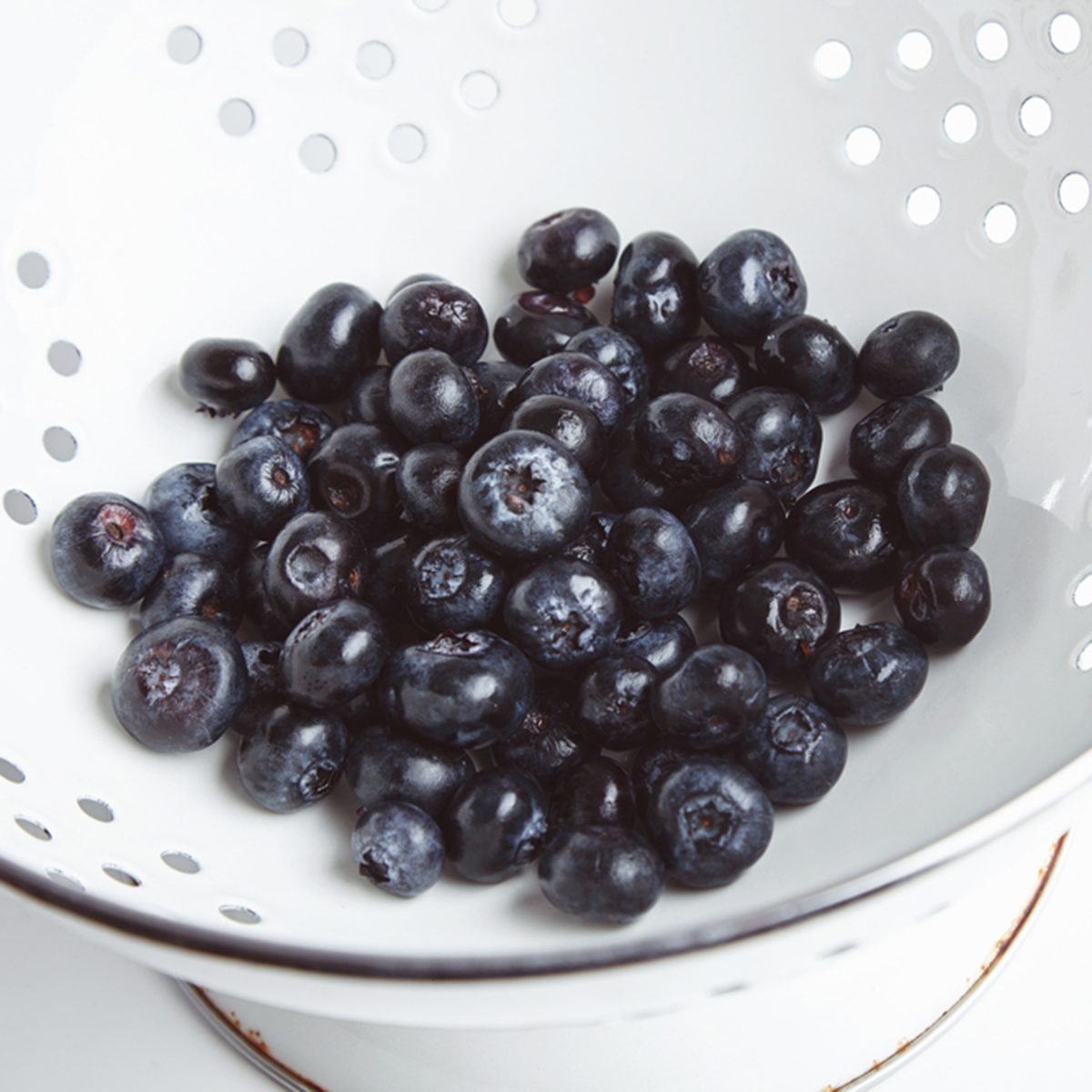 Heap of fresh blueberries in old enamel stainer