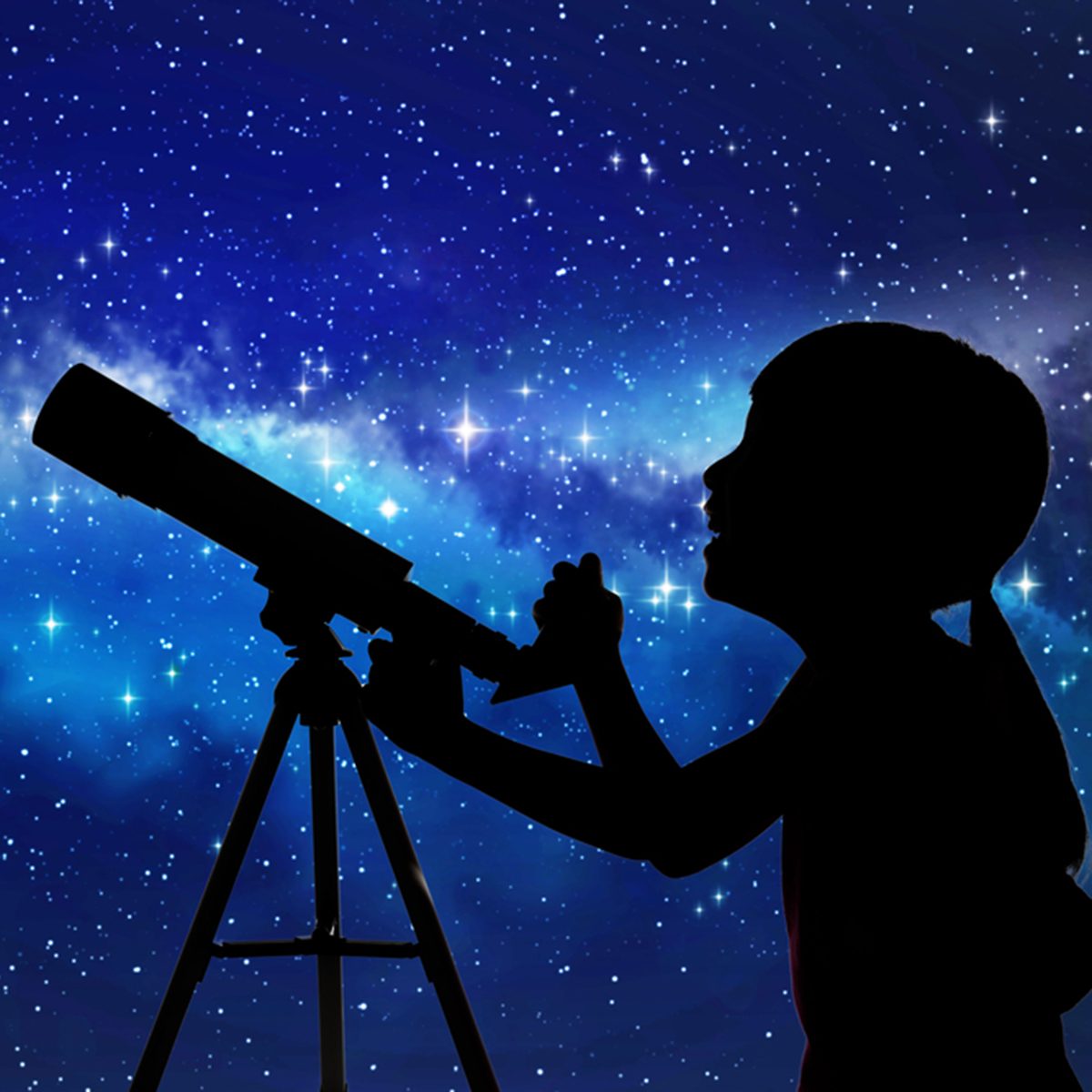 Silhouette of little girl looking through a telescope at the stars background