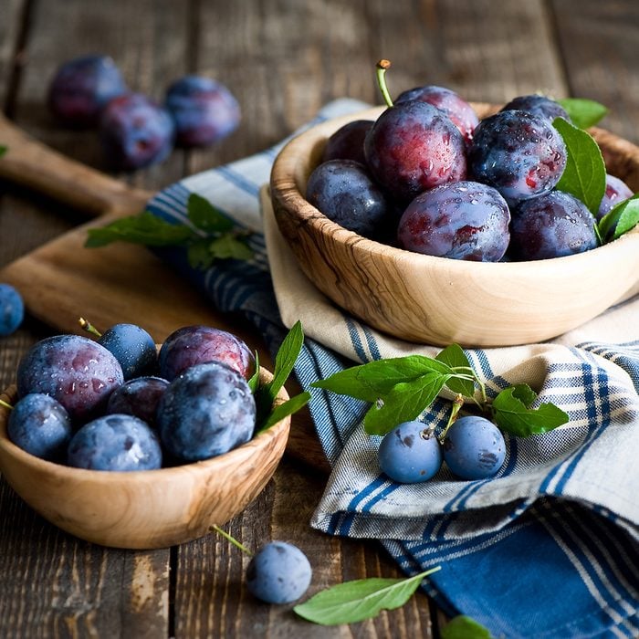 Plums in wooden bowl with napkin. stone fruit