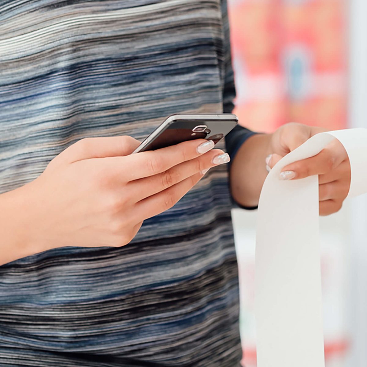 Woman shopping at the supermarket and checking a long grocery receipt