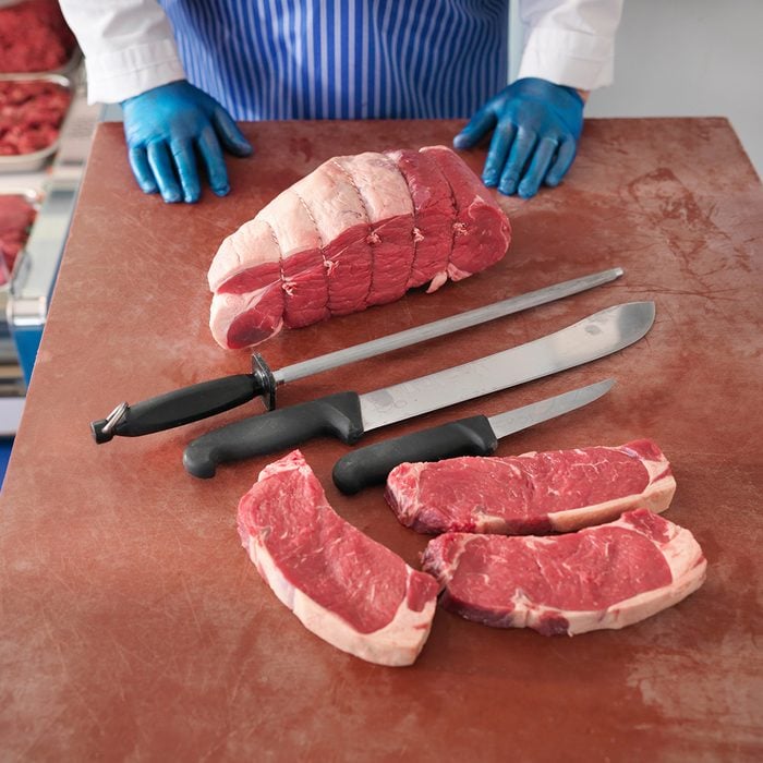 Butcher with knives and cuts of pork