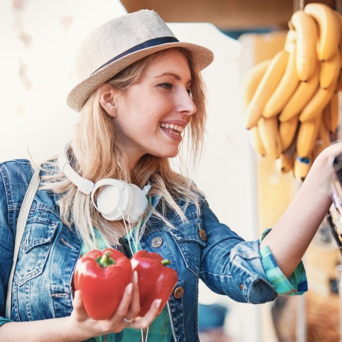 Young woman is looking for paprika at green market.