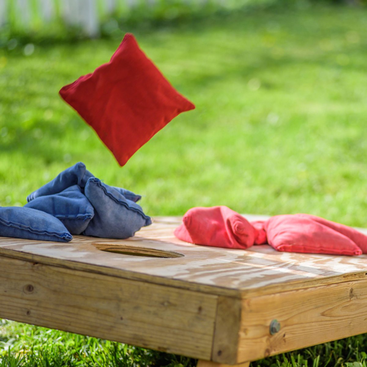 playing cornhole in backyard throwing bag in air