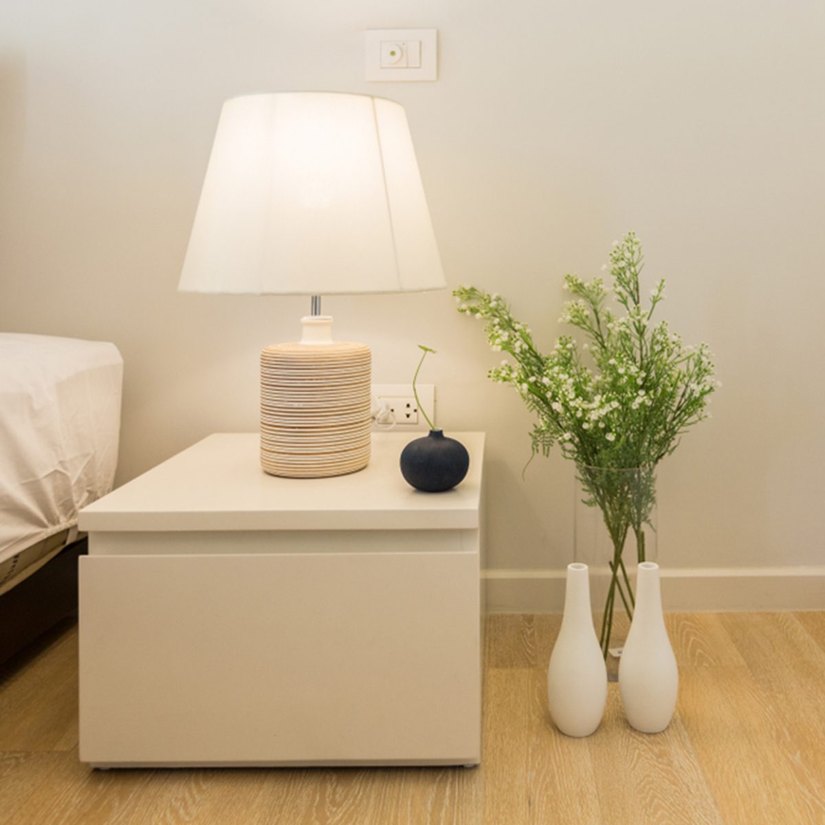 Head Lamp on night stand in bedroom with vase of flower