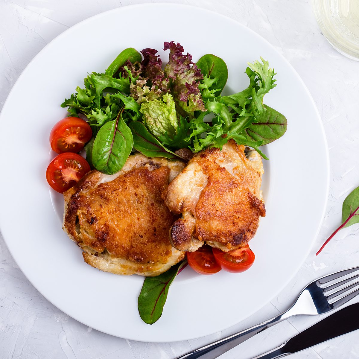 Roast Chicken Legs On White Plate Over Light Gray Plaster Texture Table