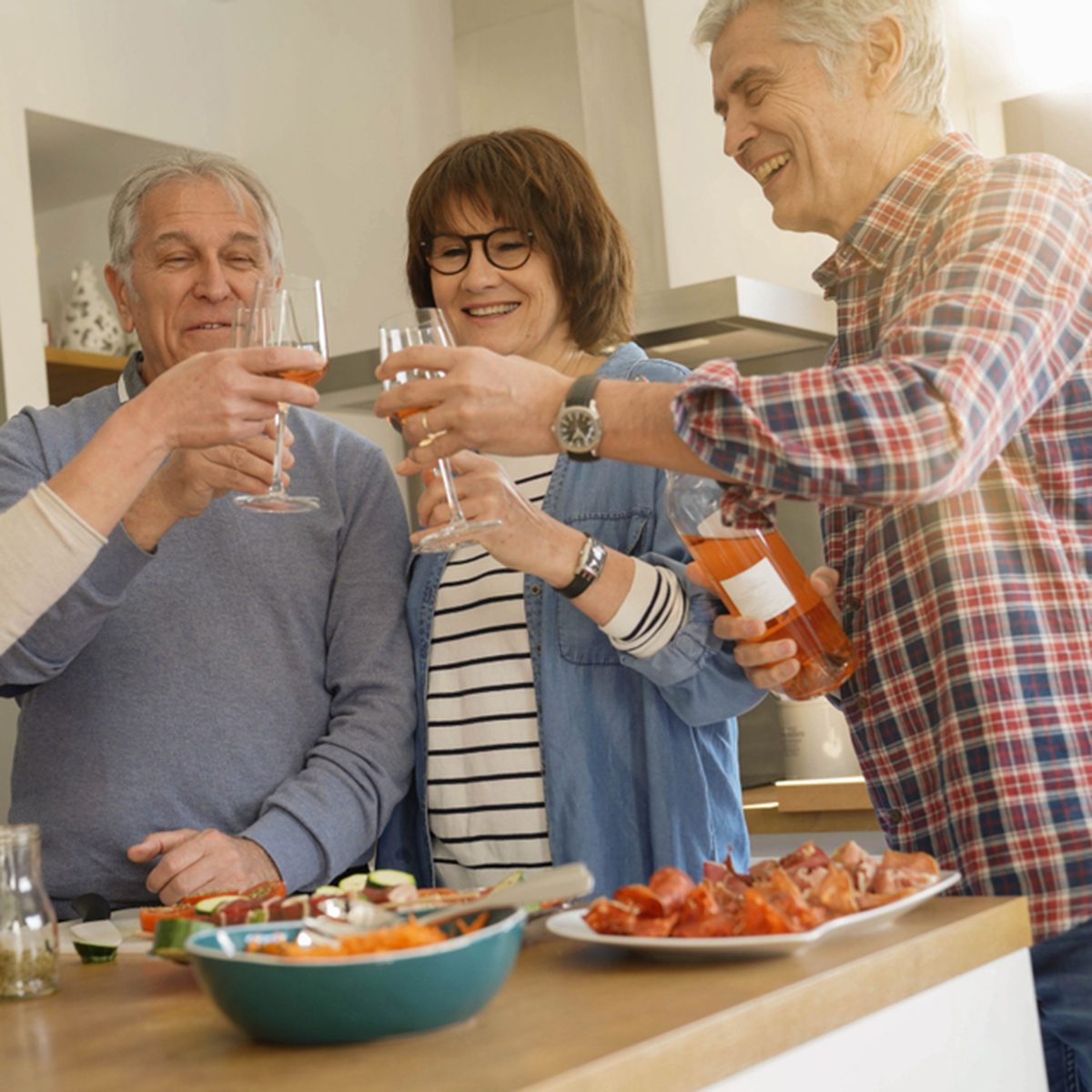 Senior people cheering with wine while preparing meal