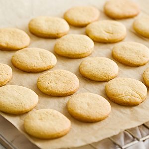 Orange butter cookies on a baking paper and wire rack.