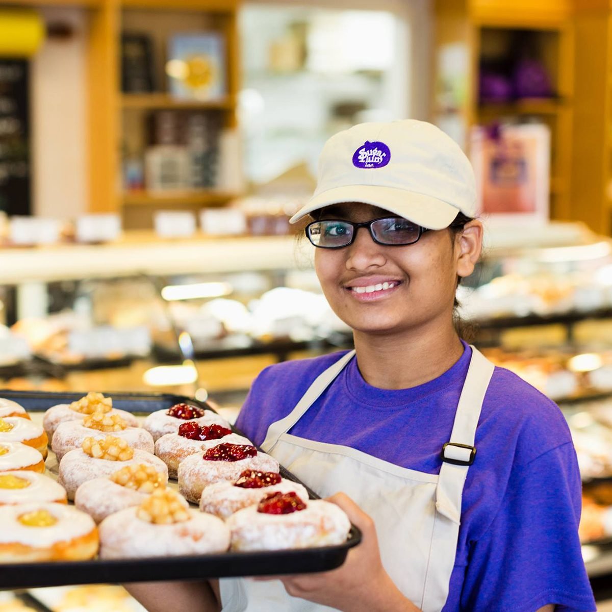 Baker holding tray of treats at Sugar Plum Bakery