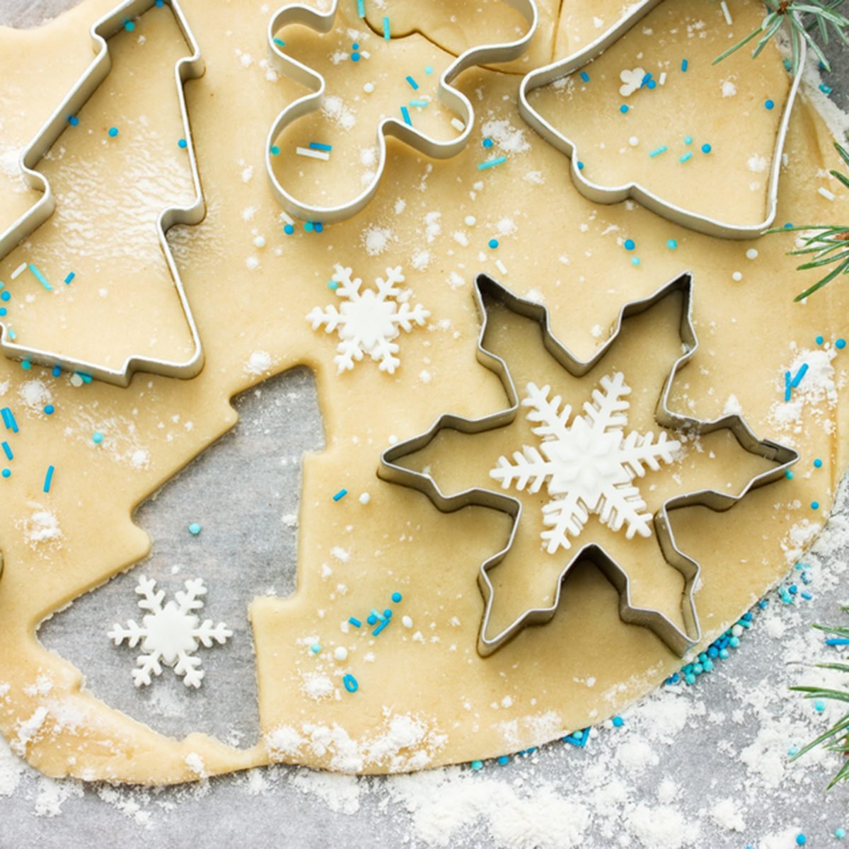 Raw dough for Christmas cookies and cookie cutters shaped glove, Christmas tree, snowflake, jingle bell, gingerbread man