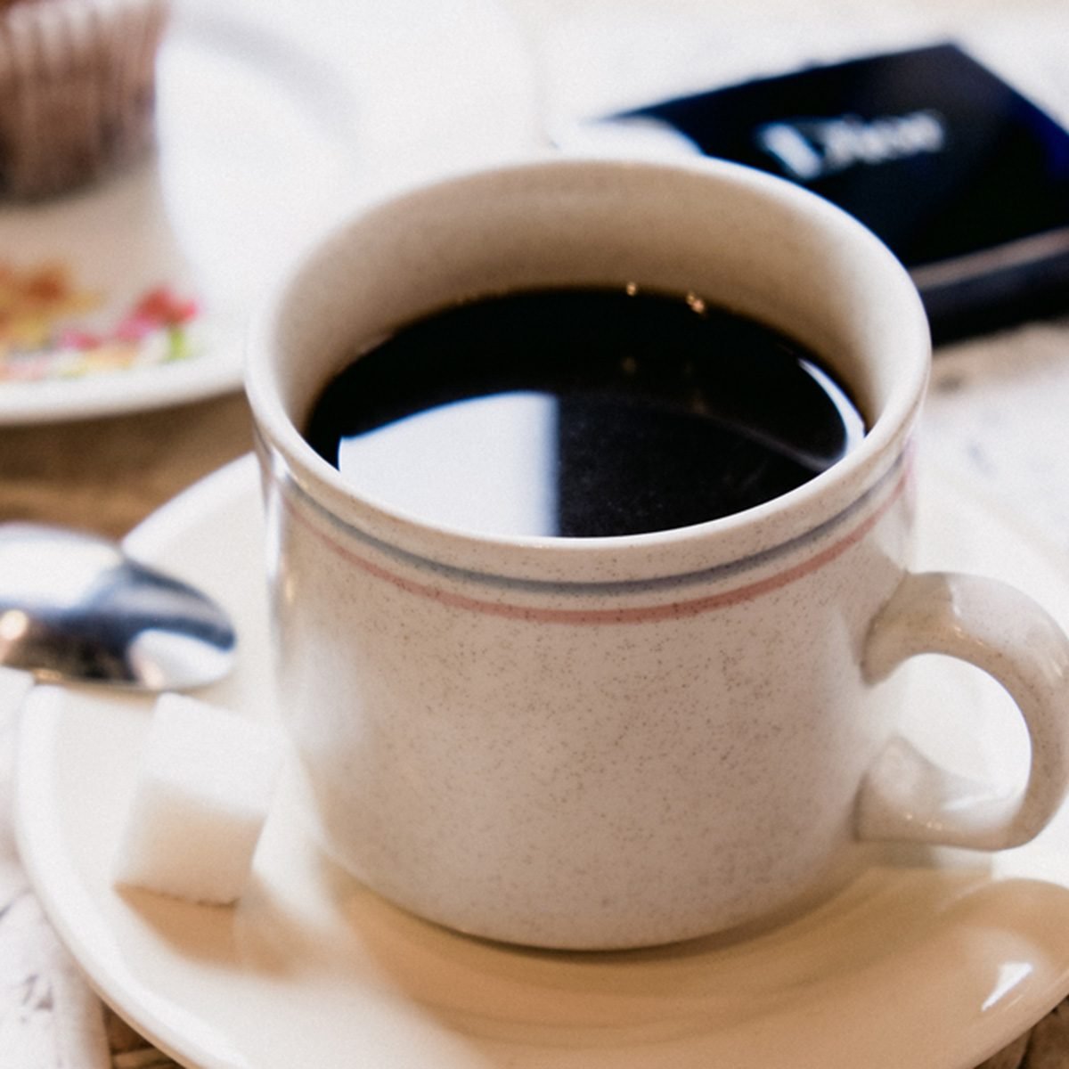 A cup of black coffee with sugar and sweet cupcake