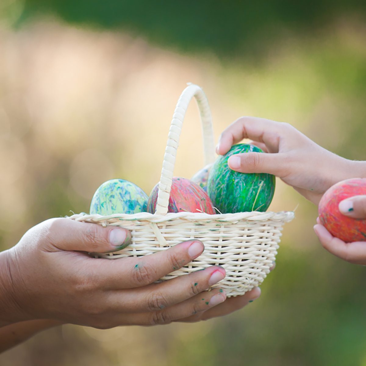 Mother and asian child girl playing and collecting colorful Easter eggs in basket together in outdoor