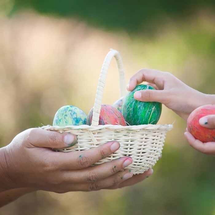 Mother and asian child girl playing and collecting colorful Easter eggs in basket together in outdoor
