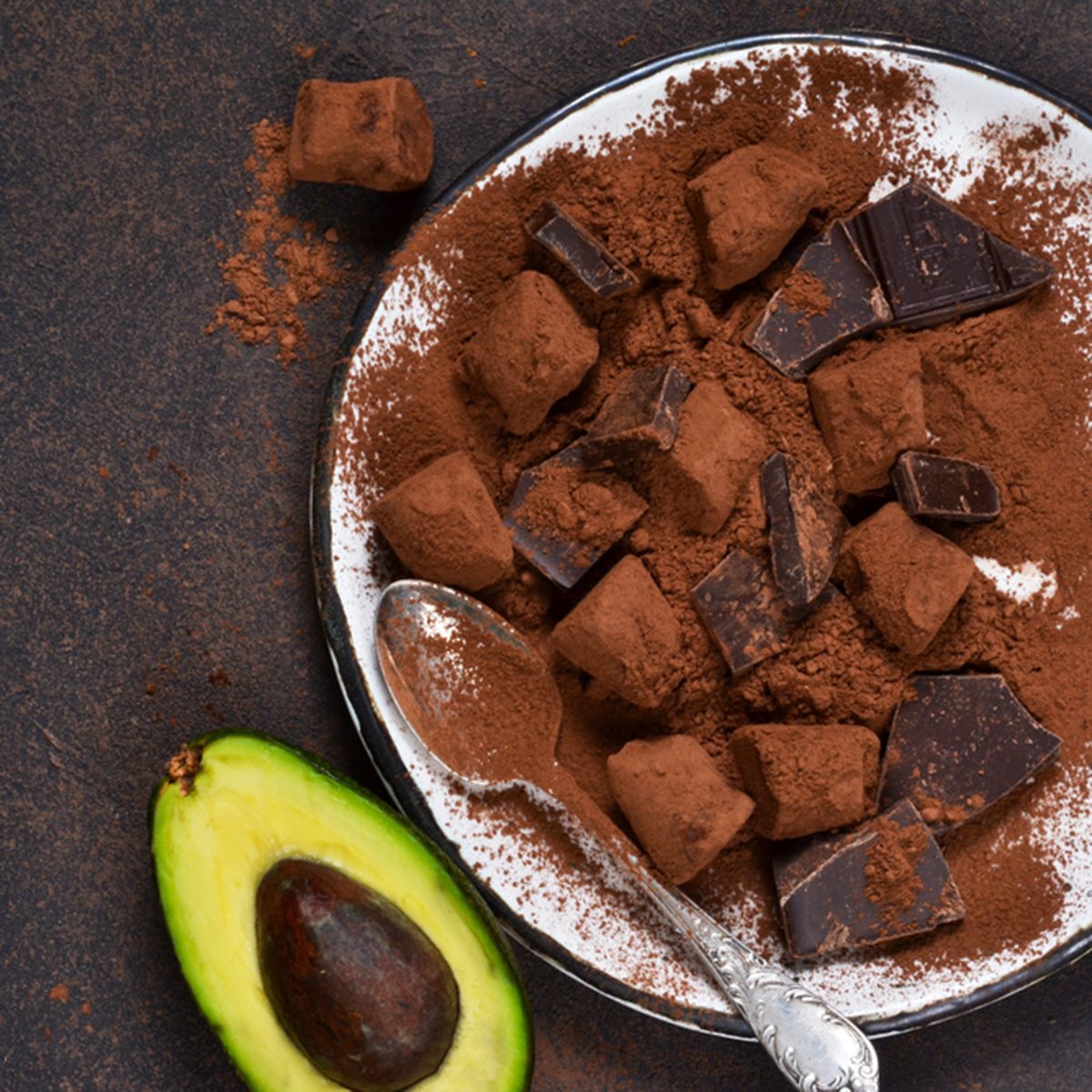 Chocolate truffle with avocado and cocoa powder on a brown background.
