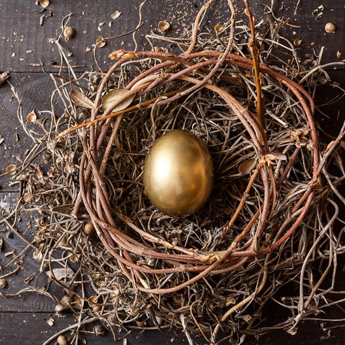 Golden egg in nest on dark vintage wooden background