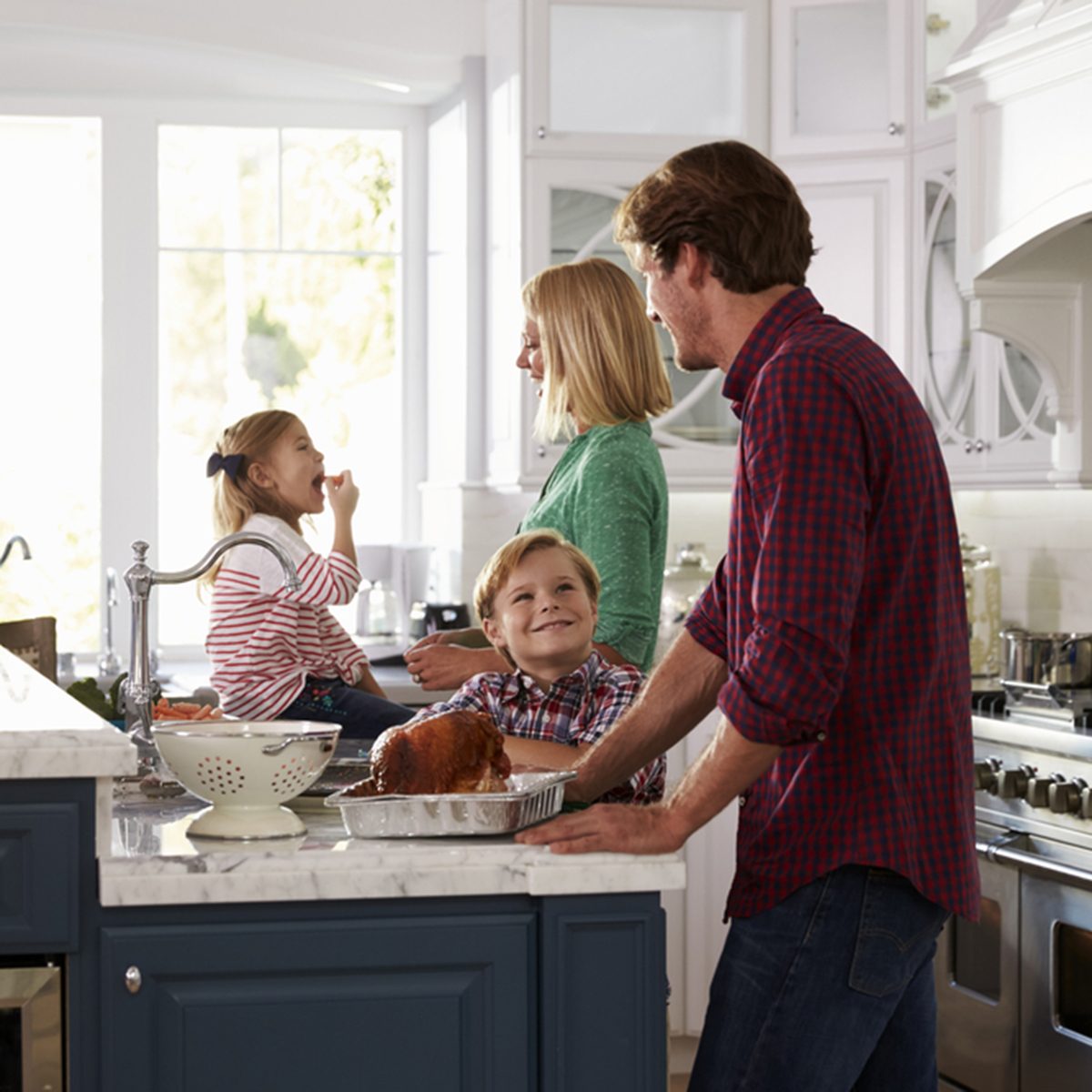 Family Preparing Roast Turkey Meal In Kitchen Together
