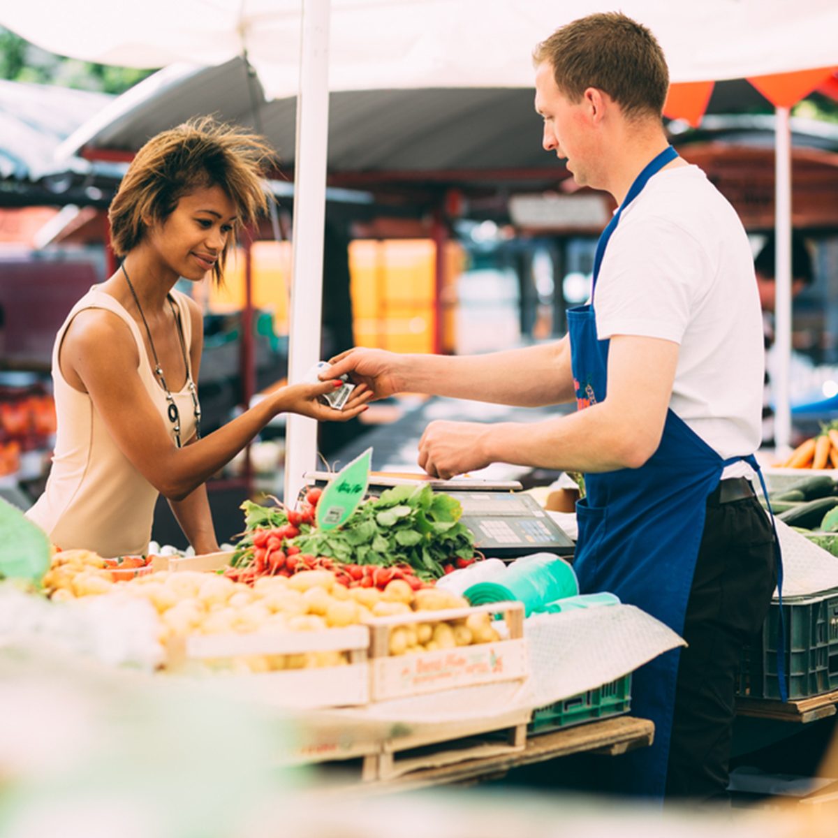 Young black woman paying for vegetables at farmer