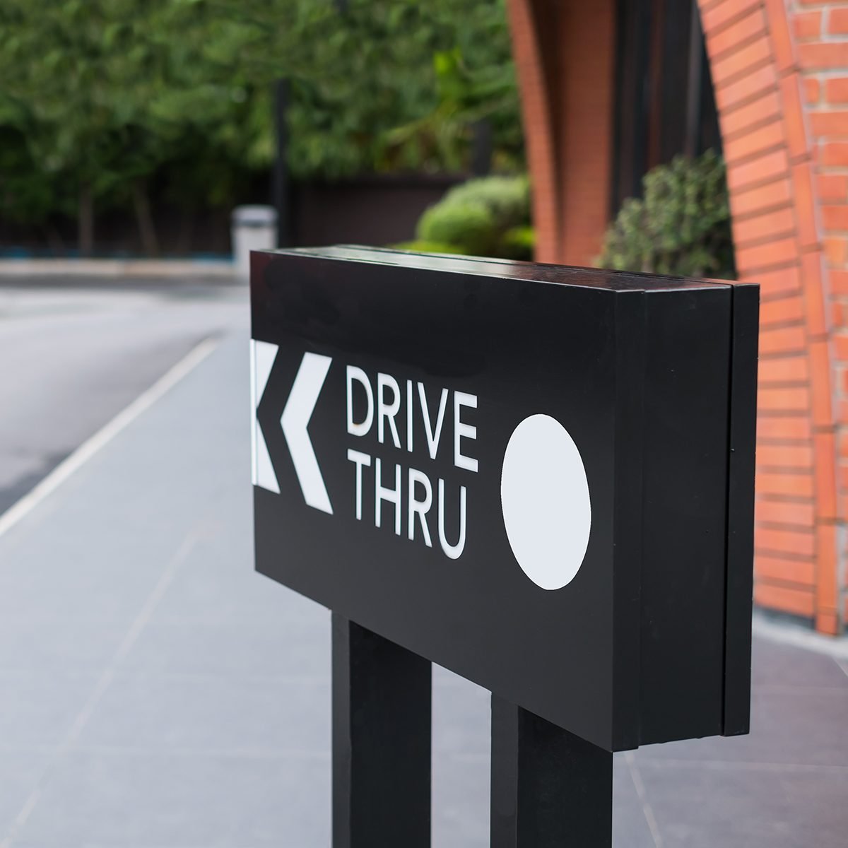 Drive thru sign with shop and road background.