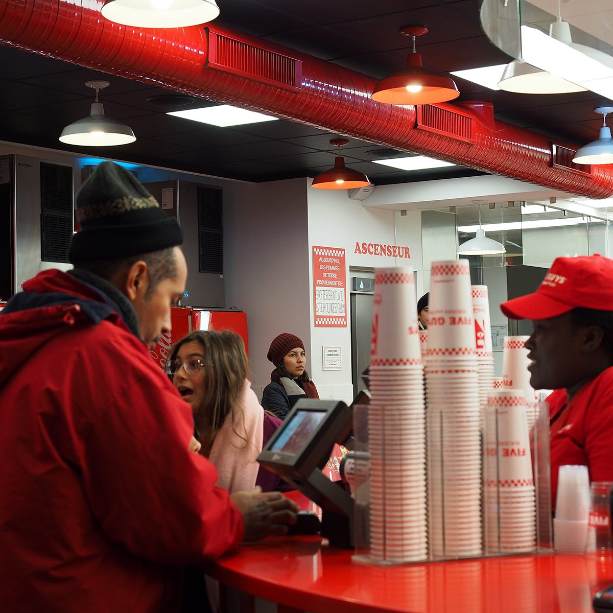 Closeup of crews working at Five Guys burger chain busily, Avenue des Champs-Élysées, Paris, France